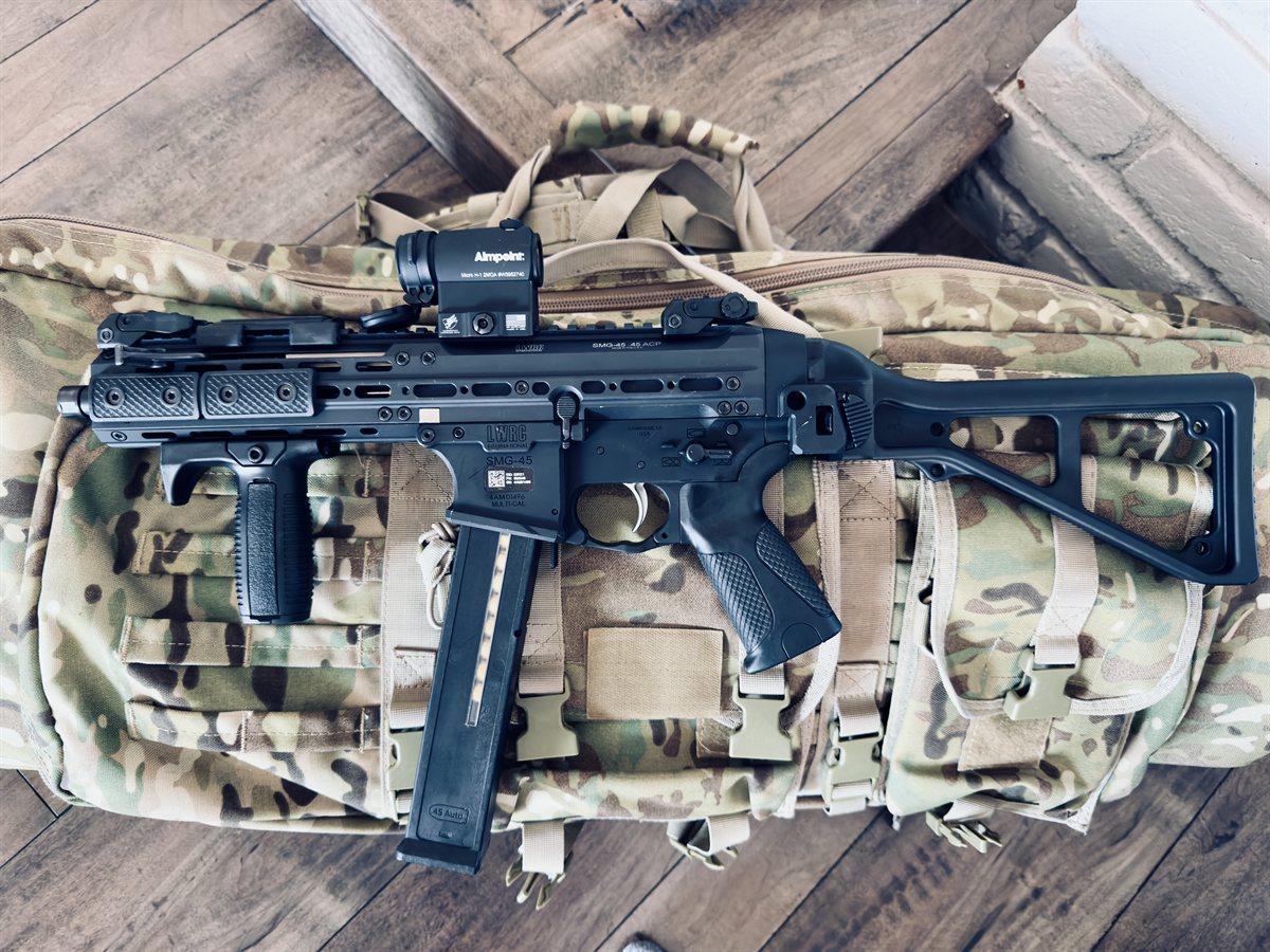 Suppressed compact rifle with red dot on a plate carrier